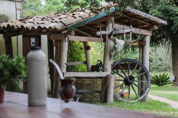 Open wooden shed amidst the greenery, with blurred mate tea gourd and thermos bottle in the foreground